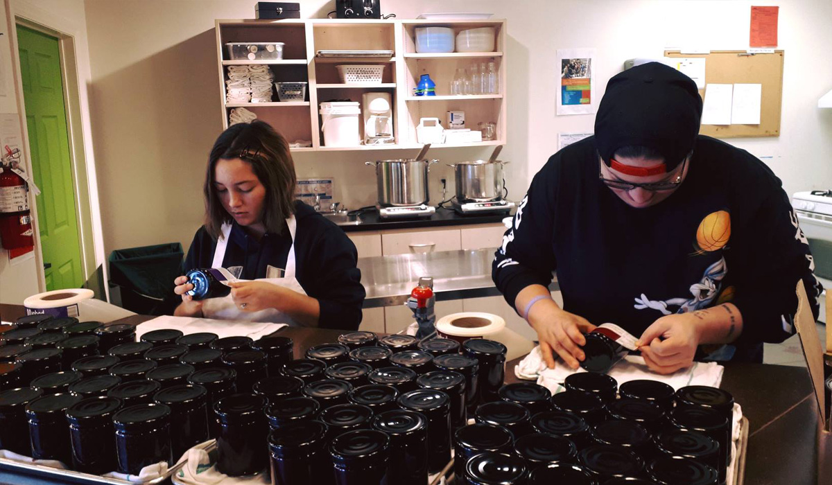 two youth labeling jars of jam