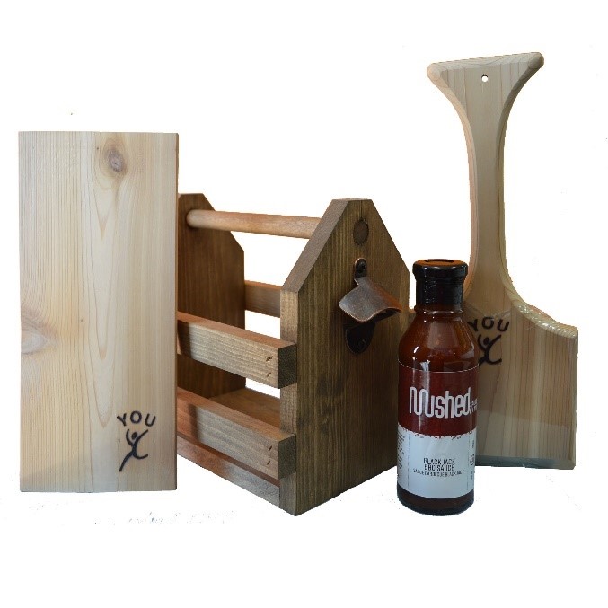 The BBQ Caddie Set features a small condiment caddy, 2 cedar grilling planks, a wooden BBQ scraper all in their natural wood grain finish, as well as a bottle of Mushed by YOU Black Jack BBQ Sauce. 