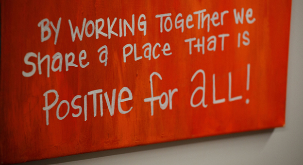 A mural at the YAC that reads: By working together, we share a place that is positive for all!