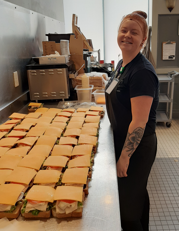 Smiling youth preparing a counter full of sandwiches
