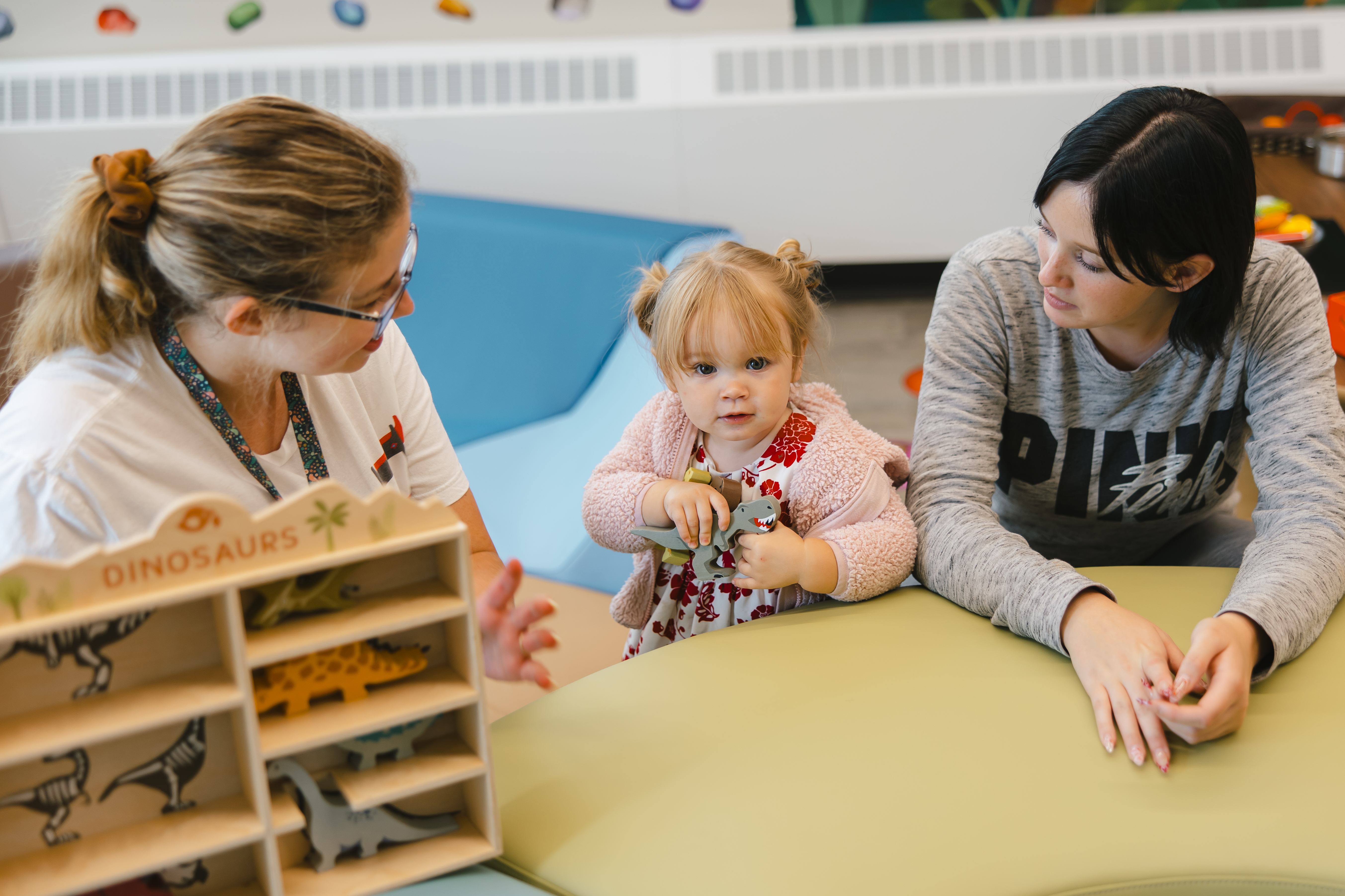 A mother looks at her toddler while playing, along with a YOU staff member, in the Parent Resource room at Joan's Place.