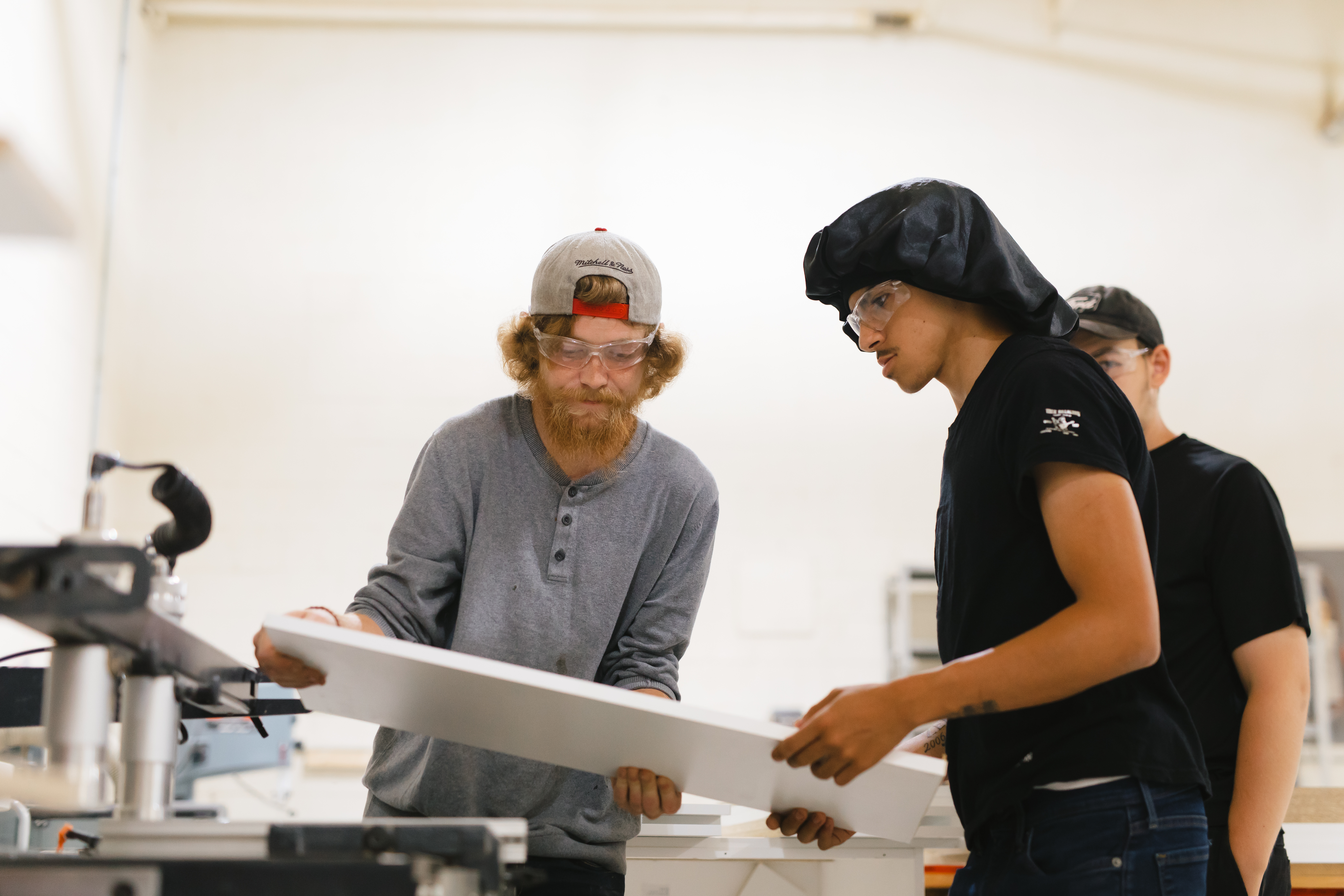 Two young people working on a piece of wood.