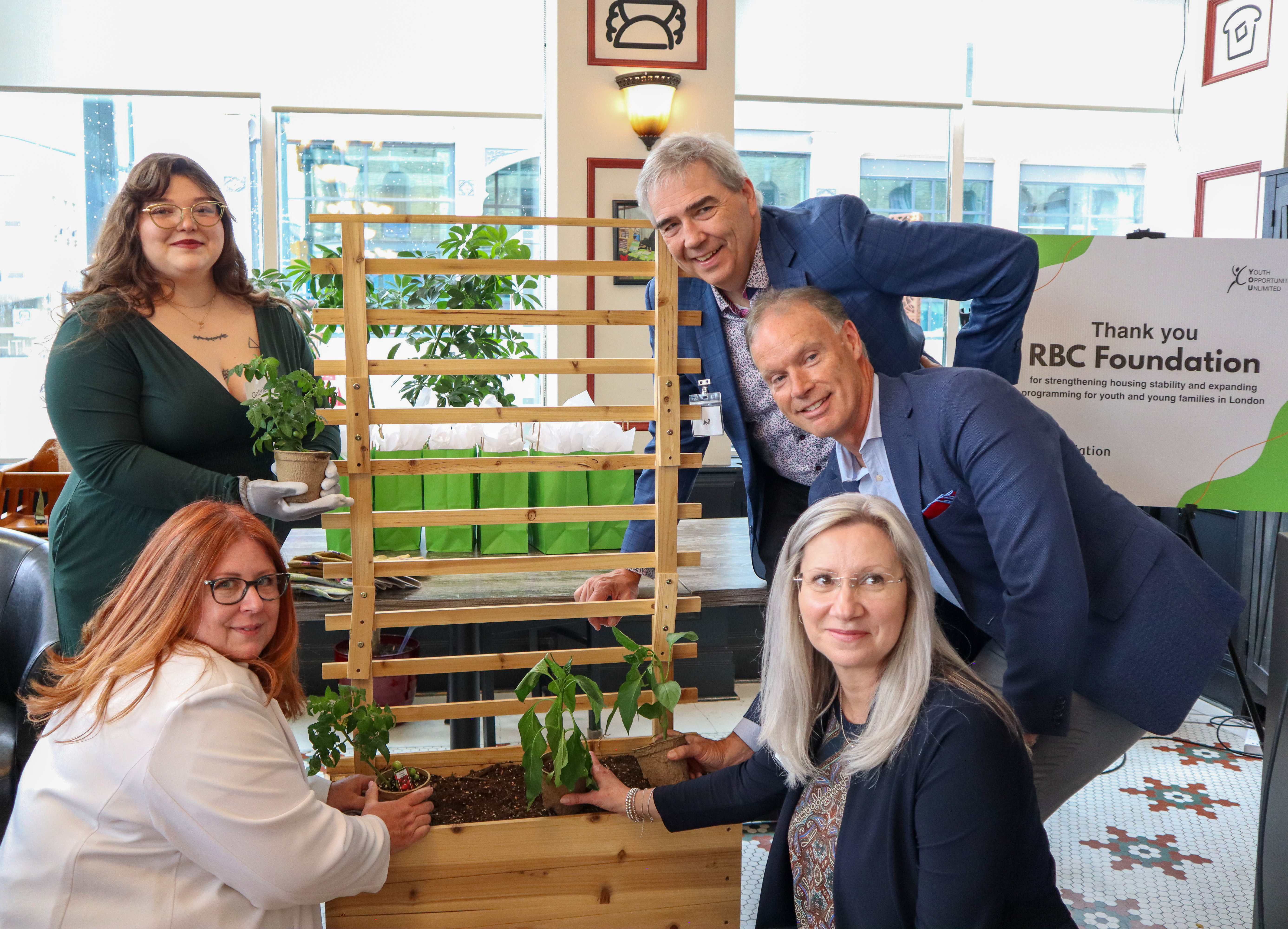 5 people around a garden planter smiling.